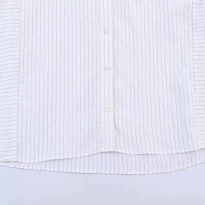 Détail d'une chemise à rayures blanches avec boutonnage et ourlet arrondi