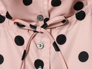 Detail of pink polka dot jacket showing grey buttons and a matching fabric waist tie