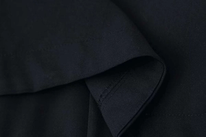 Macro shot of precise hem stitching on premium black twill fabric of long sleeve jacket