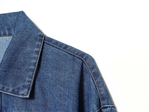 Détail du col d'une chemise en jean bleu foncé avec des surpiqûres orange contrastées