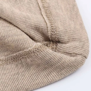 Macro shot of light brown knitted fabric detailing fine flatlock stitching and texture