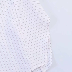 Détail de la couture latérale et de l'ourlet arrondi sur une chemise à fines rayures
