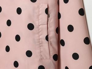 Detailed close-up of a side pocket on a pink polka dot long sleeve coat with clean stitching