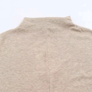 Close-up detail of beige knit maxi dress showing neck stitching and soft fabric texture