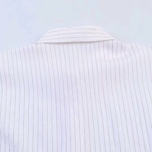 Vue détaillée du col classique et des fines rayures noires sur le tissu de la chemise blanche
