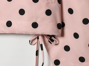 Detail of pink and black polka dot fabric showing hemline and matching drawstring tie