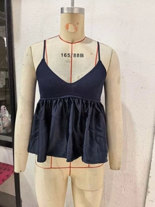 Detail of navy V-neck camisole featuring ribbed knit bodice and satin pleated hemline