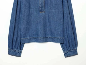 Détail d'une chemise en jean bleu avec manches lanterne et poignets boutonnés