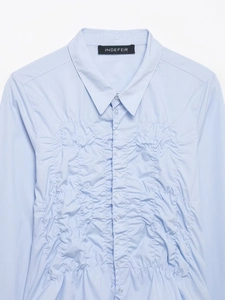Detail of light blue poplin shirt featuring stylish ruched chest design and classic collar