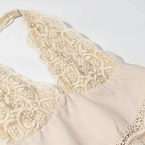 Close-up detail of beige floral lace stitching and checkered fabric on summer dress