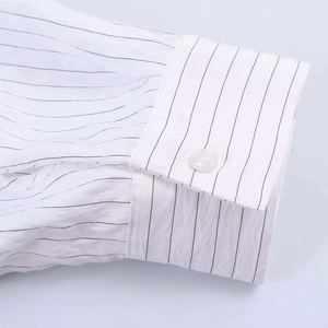 Gros plan du poignet d'une chemise à rayures gris et blanc avec détail de bouton