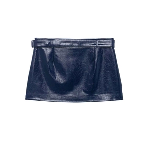 Détail d'une mini-jupe en similicuir bleu marine brillant avec ceinture assortie