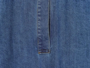 Gros plan détaillé du tissu denim bleu avec coutures orange contrastées sur la blouse