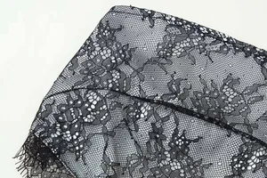 Close-up of black floral lace fabric featuring eyelash trim and intricate texture