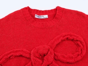 Gros plan d'un pull en grosse maille rouge avec un grand nœud décoratif sur le col rond