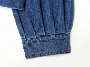 Gros plan détaillé des poignets de chemise en jean bleu foncé avec plis et surpiqûres