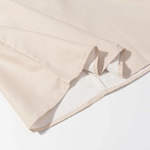 Close-up of light brown gingham fabric showing fine stitching and smooth hem texture