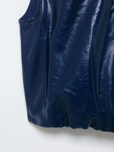 Gros plan détaillé du gilet en cuir verni bleu marine avec poche et détails d'ourlet