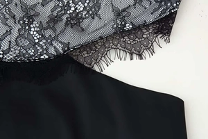 Close-up detail of black floral lace with eyelash trim on elegant satin dress
