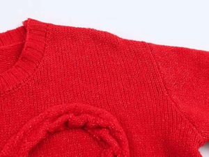 Gros plan sur le pull en maille rouge montrant le col rond côtelé et la texture du tissu