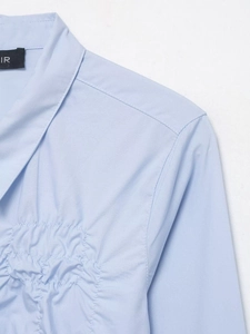 Close-up of light blue poplin shirt collar featuring detailed pleated chest design