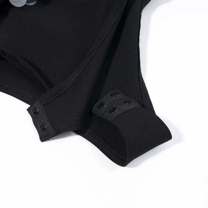 Détail de la fermeture à boutons-pression en bas d'un body noir extensible pour femme
