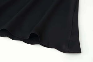 Detailed macro view of the black satin hemline with fine rolled edge stitching on the dress