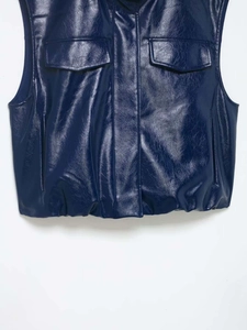 Détail du gilet en similicuir bleu marine avec texture brillante et poches de poitrine