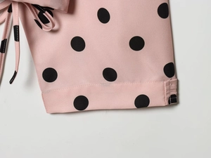 Close-up of pink polka dot blouse sleeve featuring a decorative tie knot and soft fabric