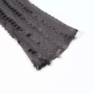Détail du tissu translucide sombre avec rangées de paillettes sur un body d'été chic
