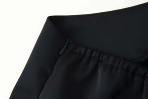 Detail shot of the black lace satin dress featuring an invisible zipper and elastic waist