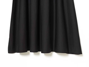 Detail of the elegant black knit dress featuring a ruffled hemline and high-quality fabric