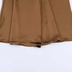 Detailed view of bronze satin skirt hem showing smooth silk texture and fine stitching