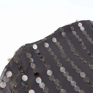 Détail du tissu transparent gris foncé avec des rangées verticales de paillettes métalliques