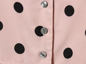 Detail view of pink polka dot fabric with high-quality pearlescent button closure