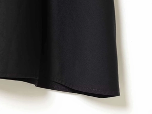 Detailed close-up of double-stitched hem on a black sleeveless knitted dress
