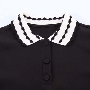 Close-up of black knit Polo top with black and white wavy collar and three matte buttons