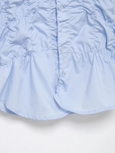 Close-up of light blue smocked poplin fabric with translucent buttons and ruffled hem