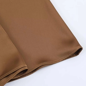 Detail of the brown satin midi skirt showing fine stitching and smooth silk-like texture