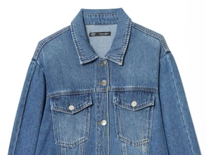 Close-up of a blue denim jacket featuring point collar and metal buttoned chest pockets
