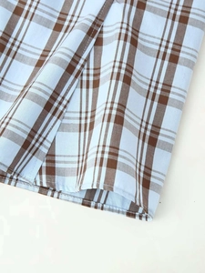 Gros plan sur la texture du tissu à carreaux bleu et marron et les coutures de la chemise