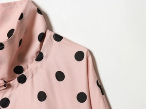 Detail of pink blouse with black polka dots showing neckline and fine stitching