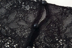 Close-up of black floral lace fabric with three round buttons on a satin summer dress