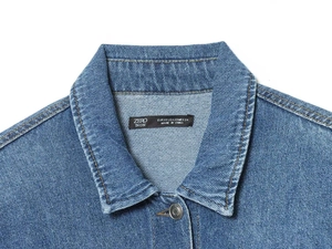Detail of blue denim jacket collar with brand label and heavy cotton twill texture