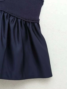 Detail view of navy blue knit top and satin fabric contrast stitching on the dress