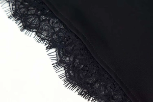 Detail shot of the delicate eyelash lace hem and hollow embroidery on a black dress