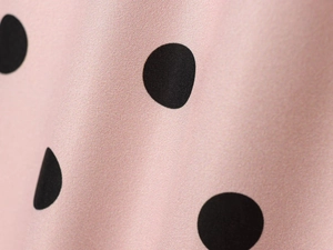 Detail shot of the pink fabric with black polka dots showing the twill woven texture