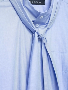 Detail of light blue cotton shirt featuring an adjustable tie-knot collar and soft texture