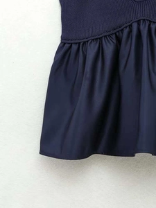 Detailed close-up of navy blue knit rib fabric and pleated seam stitching on the dress