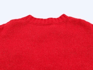 Détail du col rond et de la maille fine d'un pull rouge avec nœud tridimensionnel
